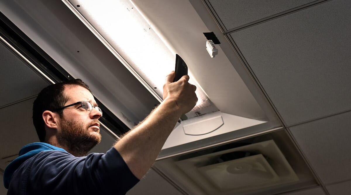 An installer uses a cell phone to configure a connected lighting system in a Next Generation Lighting Systems (NGLS) living lab. [Photo credit: Image courtesy of Pacific Northwest National Laboratory (PNNL) and NGLS.]